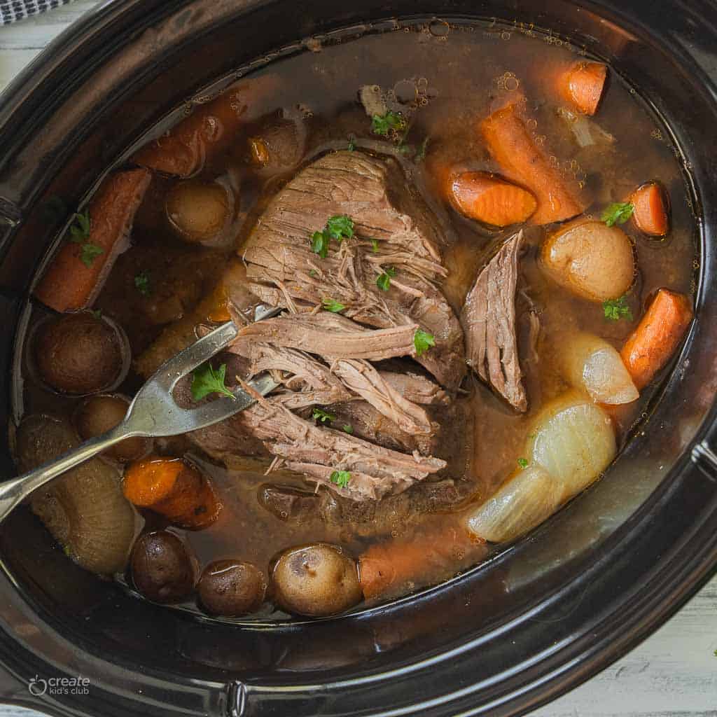 roast being shredded in crockpot