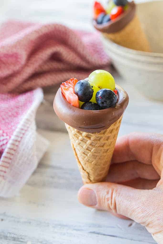 hand holding gluten free waffle cone filled with fruit