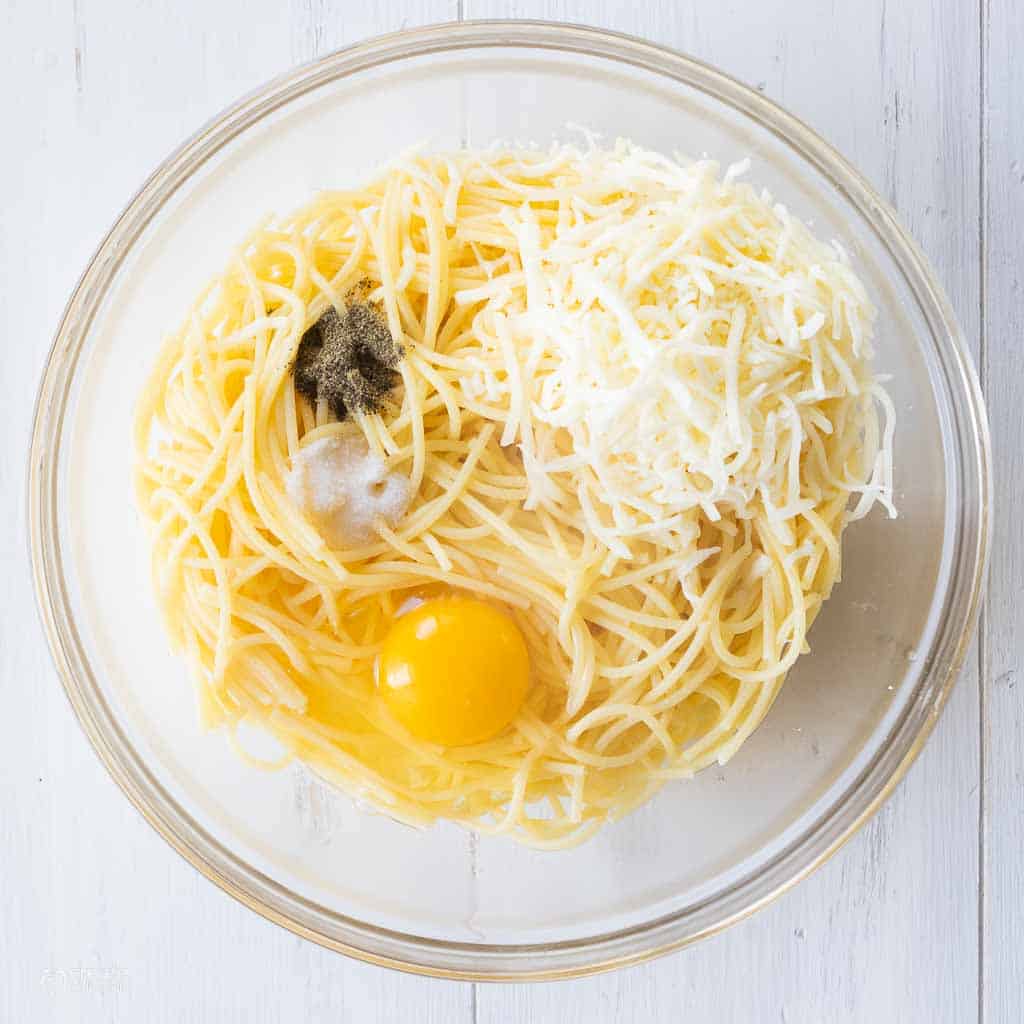 spaghetti, shredded cheese, egg and spices in mixing bowl