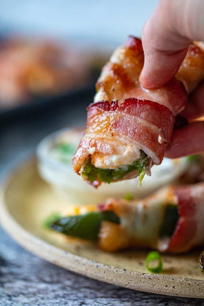 hand holding bacon wrapped jalapeno pepper