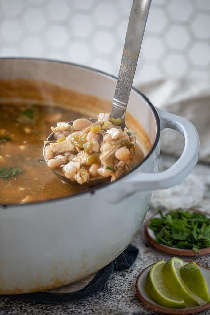 ladle scooping green Chili chicken soup from pot