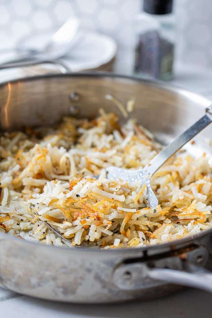 cooked hashbrowns in a skillet with spatula