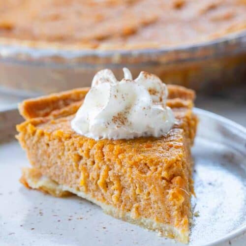 slice of sweet potato pie on plate with dollop of whipped cream