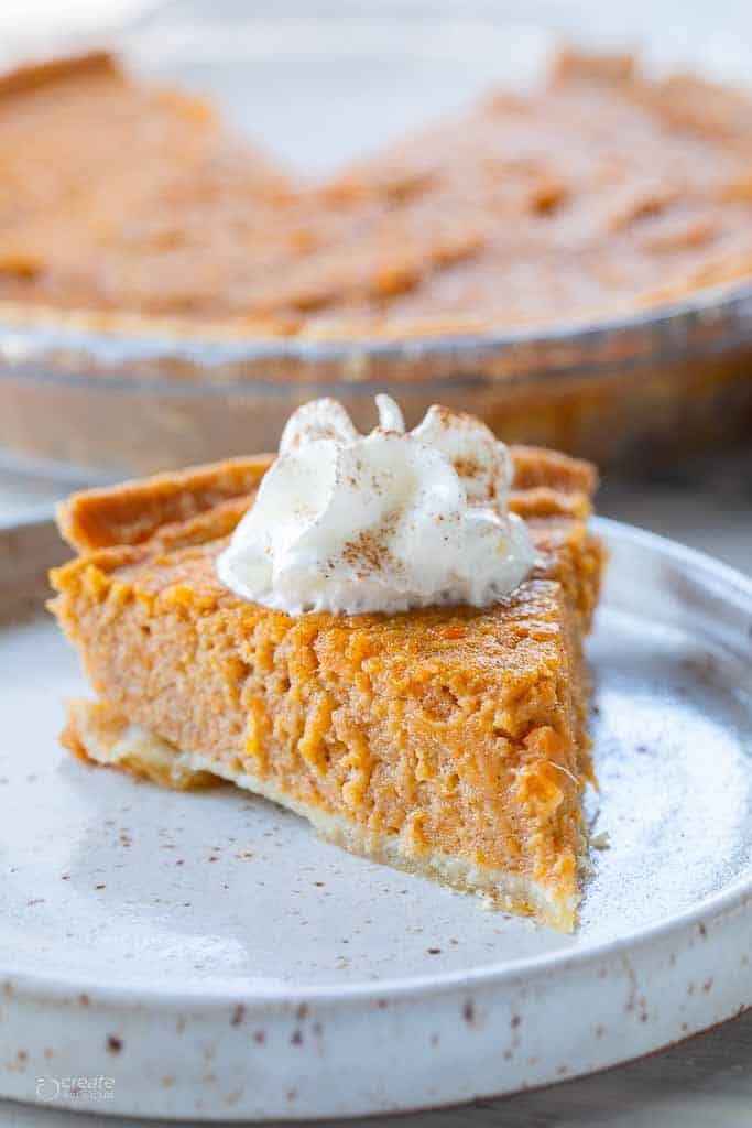 slice of sweet potato pie on plate with dollop of whipped cream