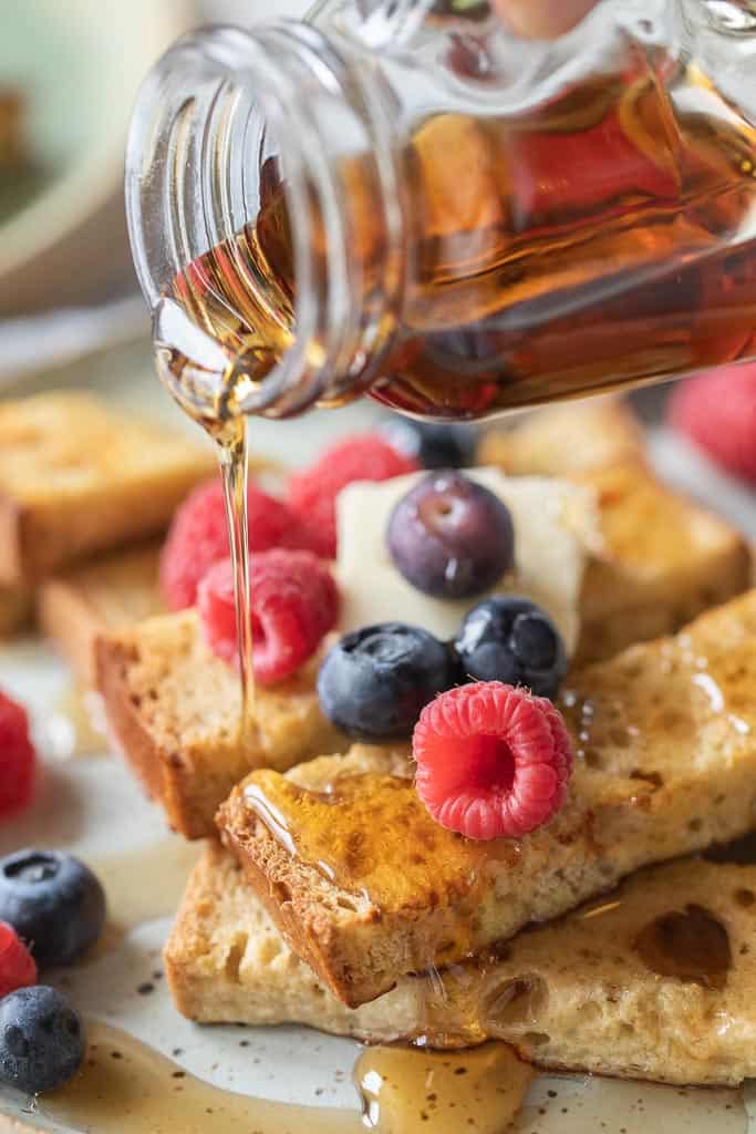 maple syrup drizzled over French toast sticks topped with fruit