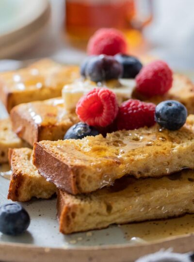 Close up of French toast sticks with maple syrup and fresh berries.