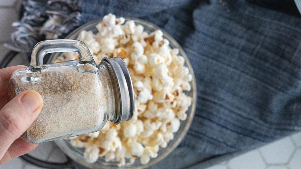 hand shaking caramel popcorn seasoning on popcorn