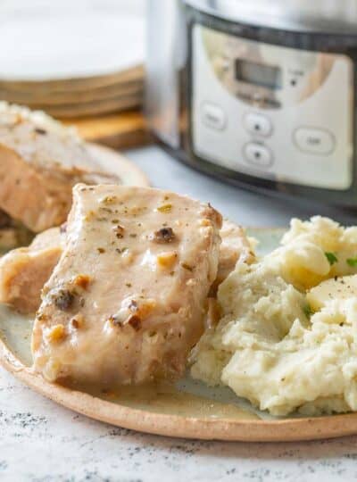 gravy covered pork chops on plate with potatoes