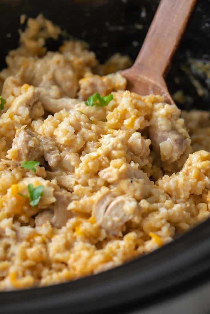 wooden spoon in crockpot with chicken and rice casserole