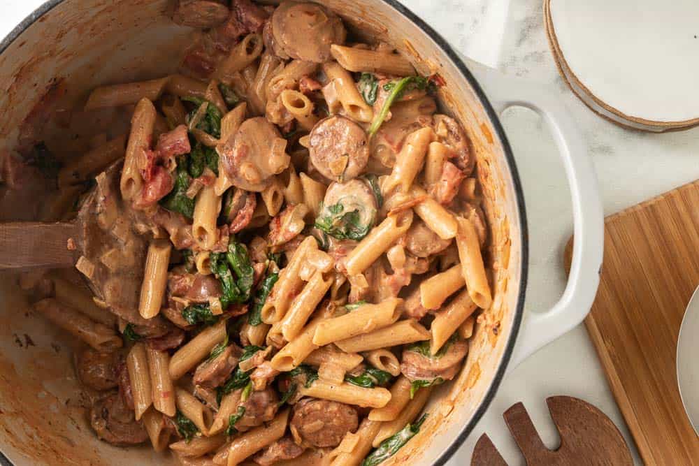 wooden spoon stirring creamy chicken sausage pasta