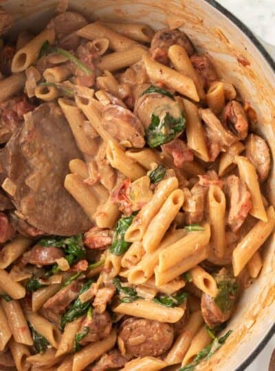 wooden spoon stirring pasta and sausage