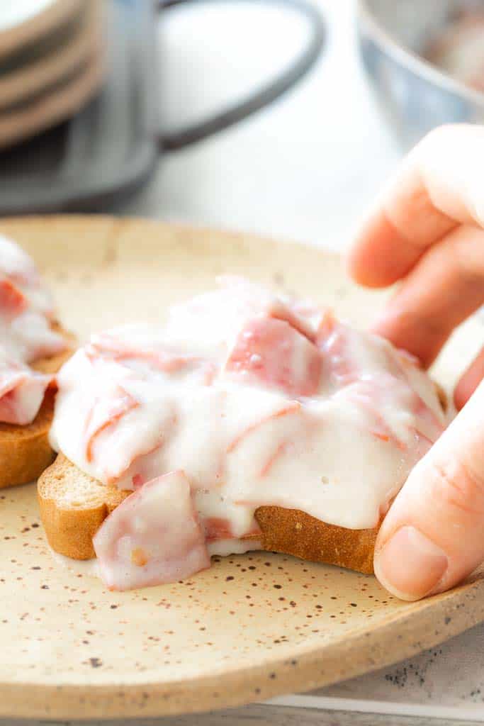 hand picking up toast topped with chipped beef
