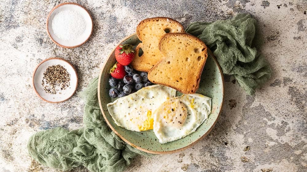 top down shot of over easy eggs with toast and berries