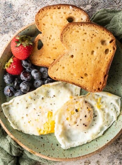 over easy eggs on plate with toast and berries