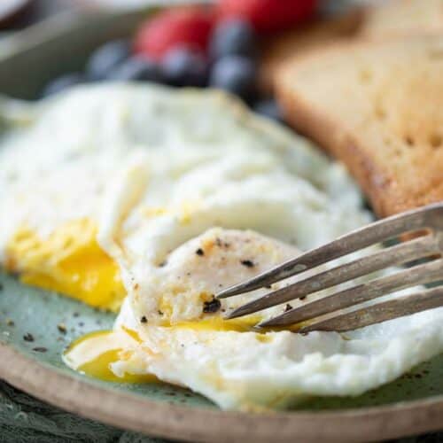 fork scooping into over easy eggs