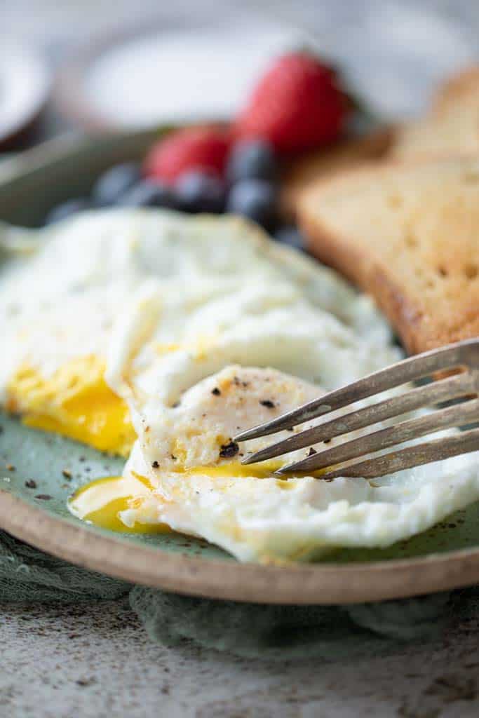 fork scooping into over easy eggs