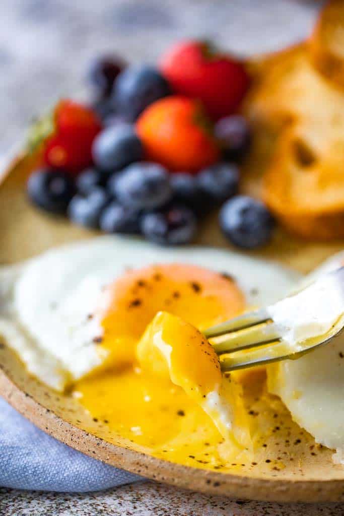 fork scooping into sunny side up eggs