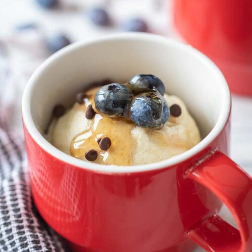 pancake in a mug topped with syrup and fruit