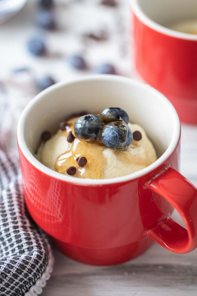 pancake in a mug topped with syrup and fruit