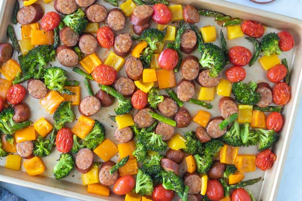 close up view of roasted veggies and sausage on sheet pan