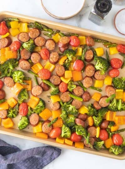 top down shot of roasted vegetables with slices of sausage on pan