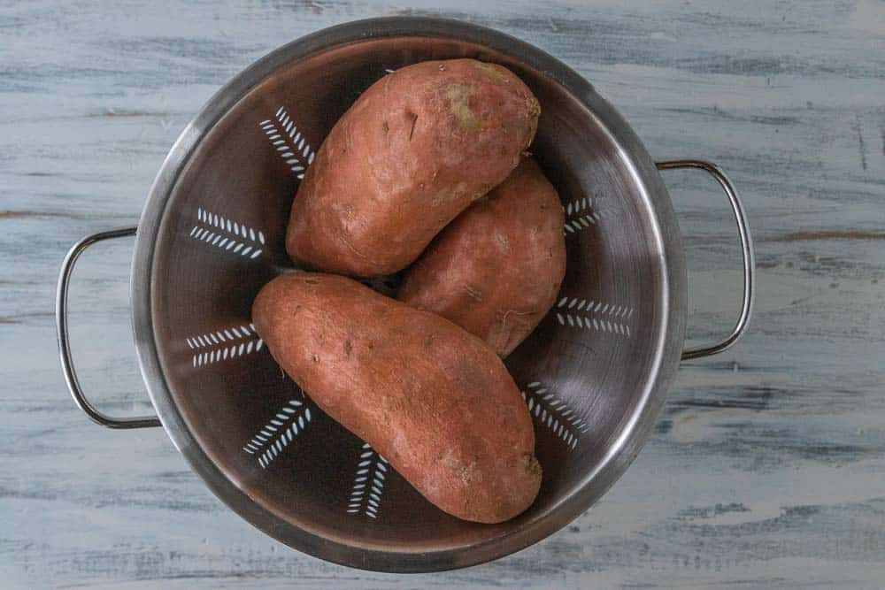 three sweet potatoes in a colander