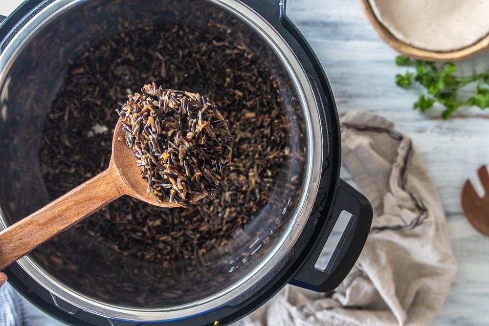 wooden spoon scooping wild rice from instant pot