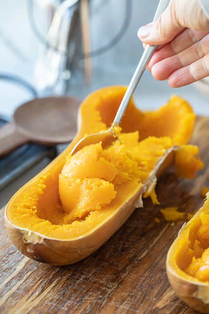 spoon scooping butternut squash from skin