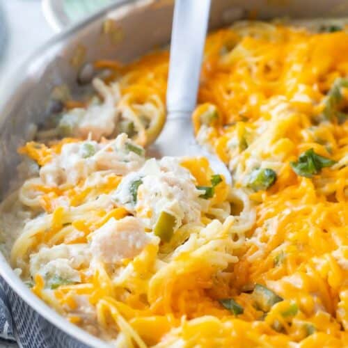 large spoon in skillet of cheesy chicken pasta