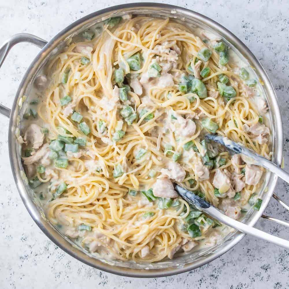 creamy chicken pasta stirred in pan with tongs