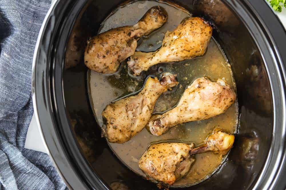 top down view of seasoned chicken legs in slow cooker