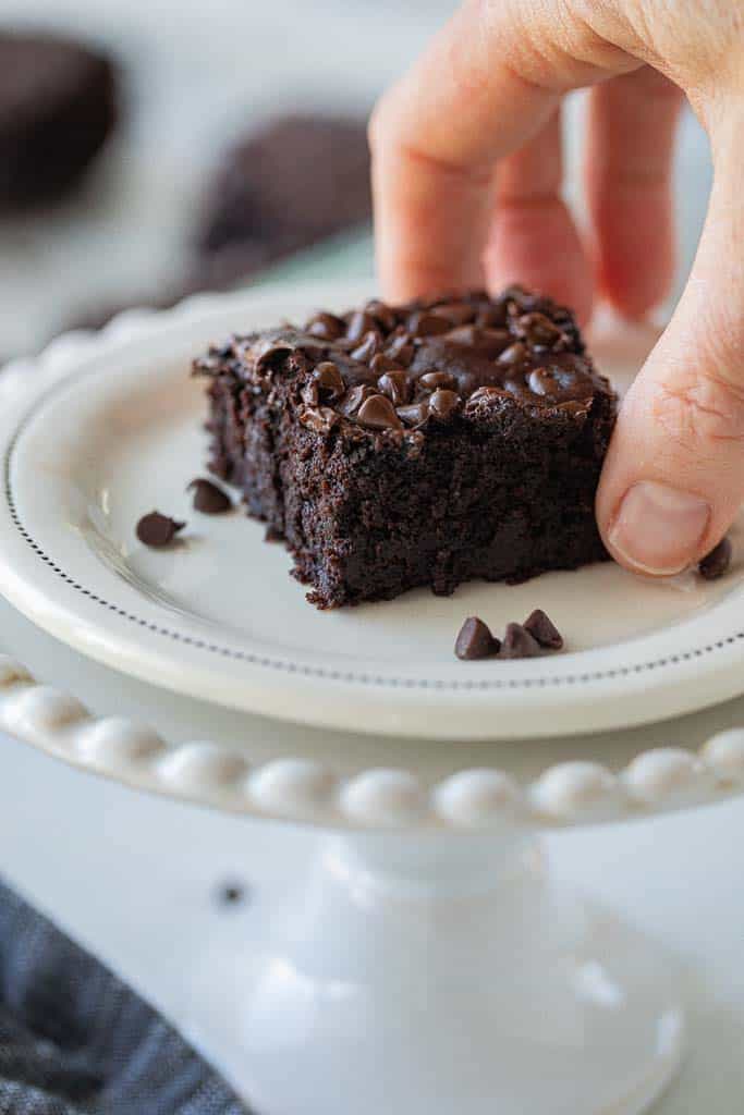 hand picking up a black bean brownie topped with mini chocolate chips