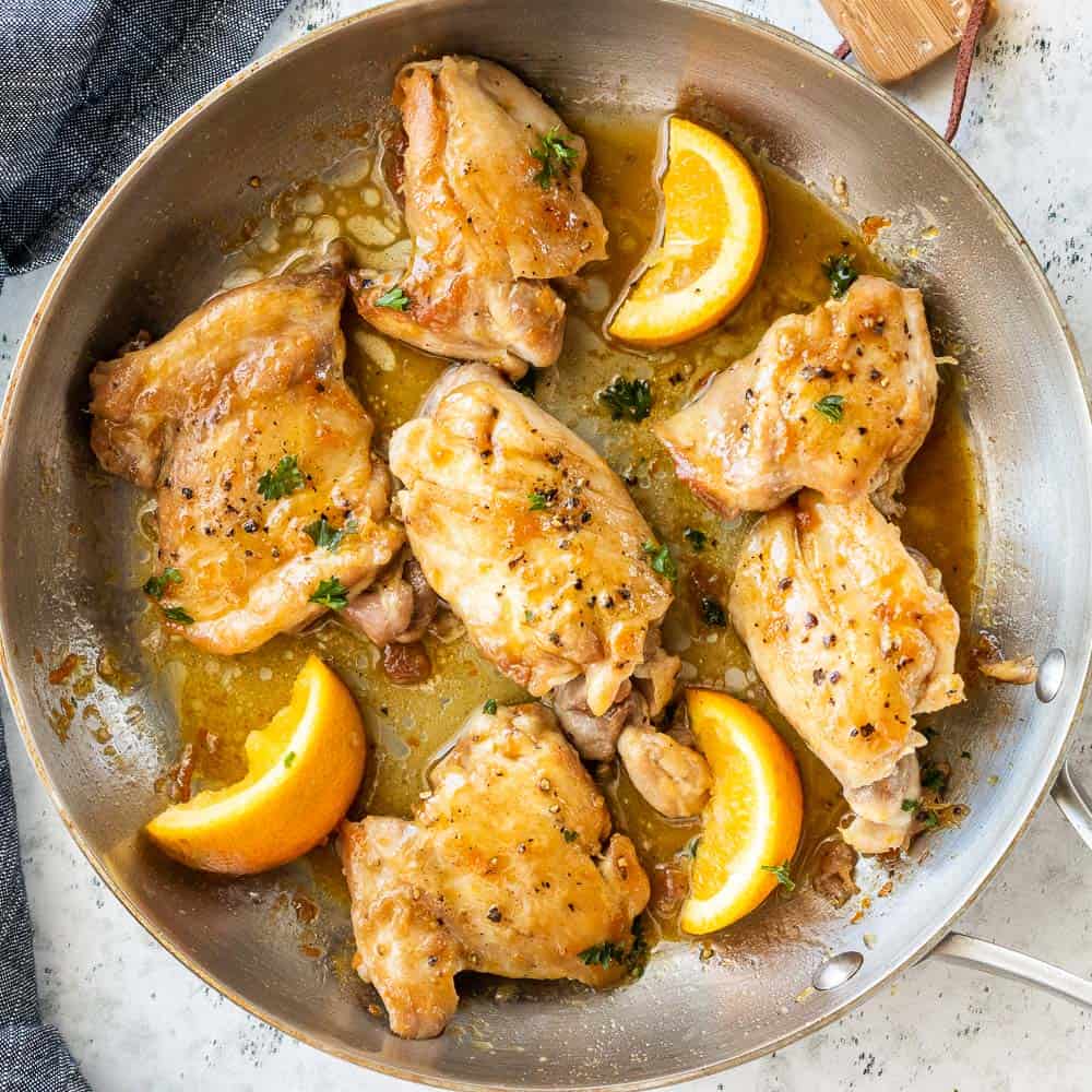 top-down view of seasoned boneless skinless chicken thighs in skillet