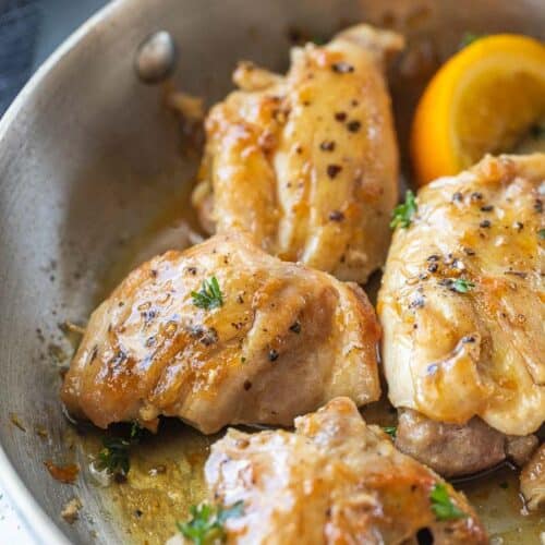 seasoned chicken thighs and orange wedges in a skillet