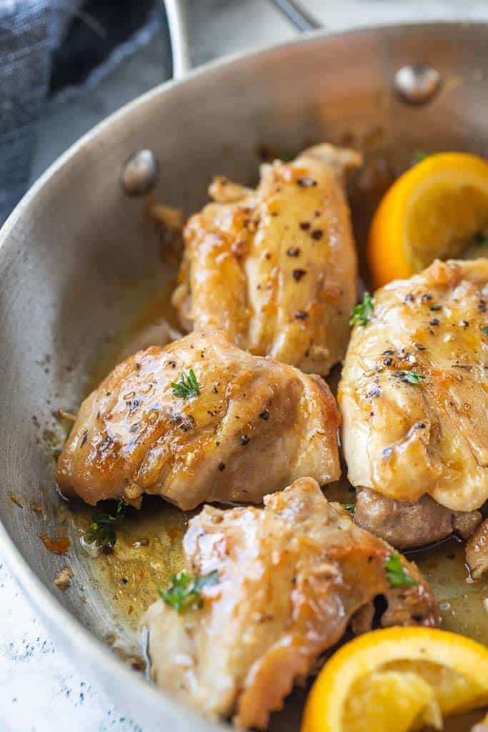 seasoned chicken thighs and orange wedges in a skillet