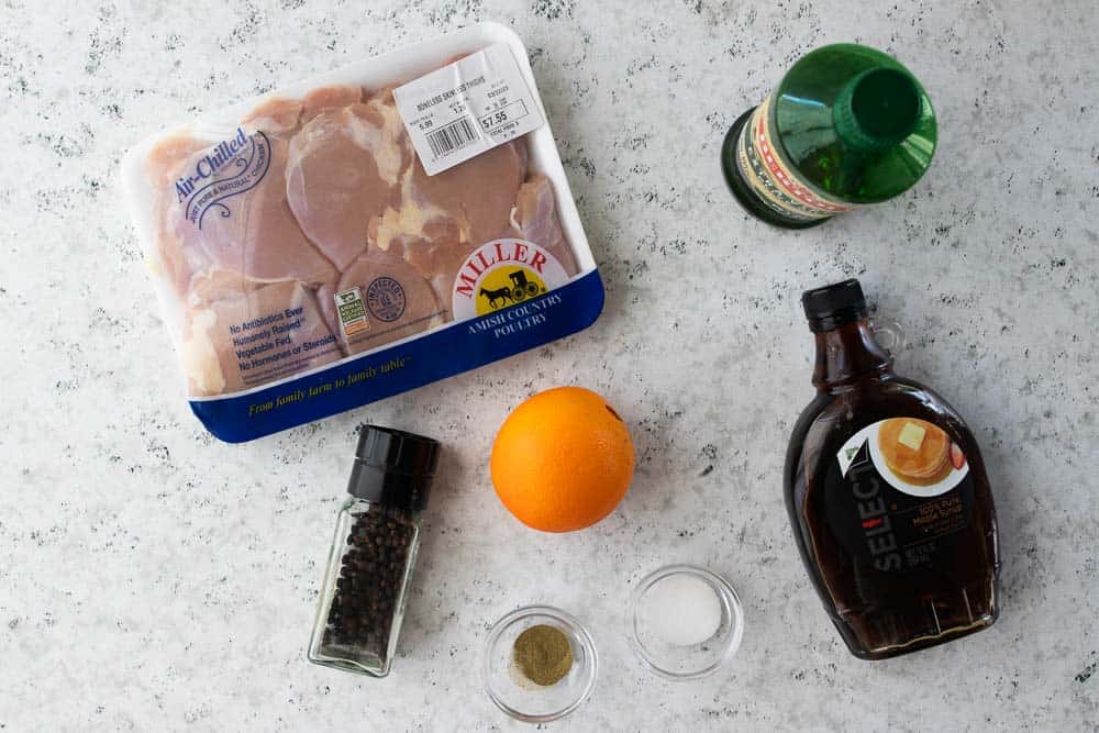 chicken thighs, olive oil, spices, maple syrup and an orange on the counter