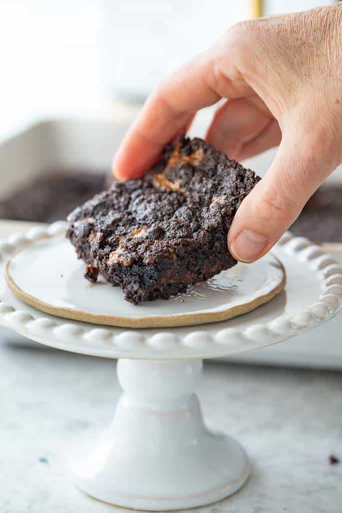 hand picking up caramel bar from cake stand