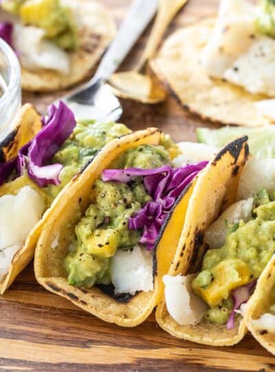 close up of tacos with cod, guacamole and cabbage