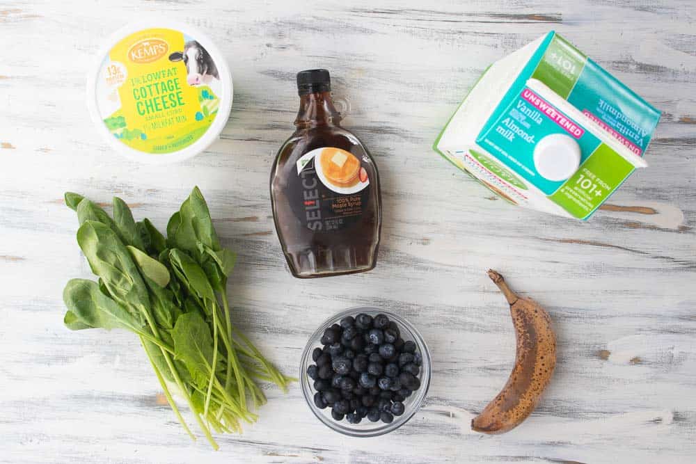 cottage cheese, spinach, maple syrup, blueberries, almond milk and banana on counter