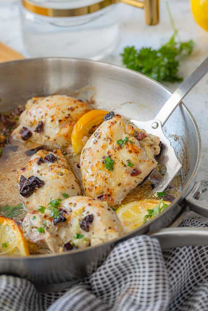 spatula scooping seasoned chicken thigh from skillet