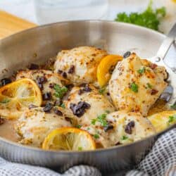 spatula scooping seasoned chicken thigh from skillet