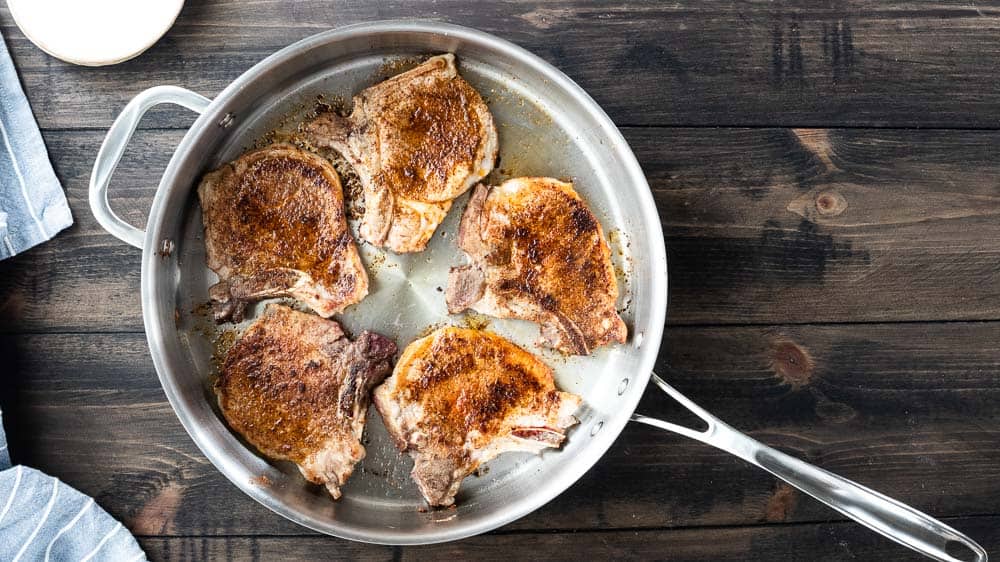 top down shot of five seared pork chops in skillet