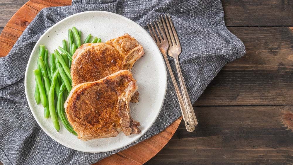 top down view of two pork chops and green beans on plate