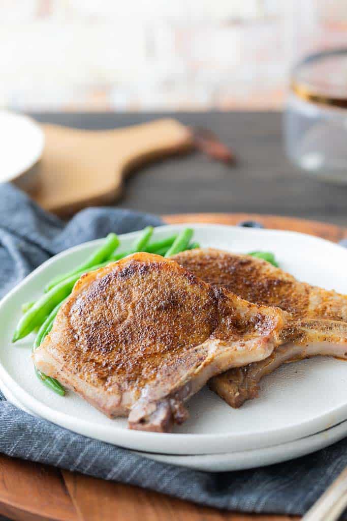 two pork chops on a plate with green beans