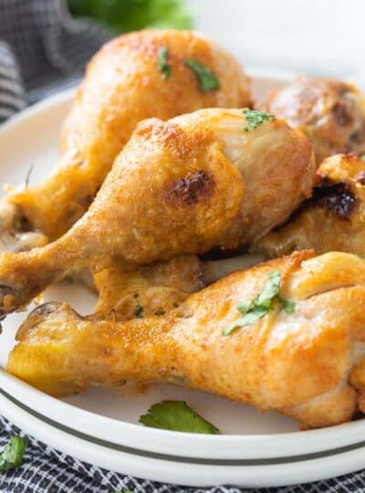 close up view of stacked chicken drumsticks on a plate