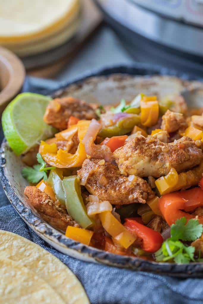 sliced and sauteed peppers in bowl with seasoned chicken