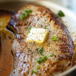 seasoned sirloin steak in pan topped with melting butter