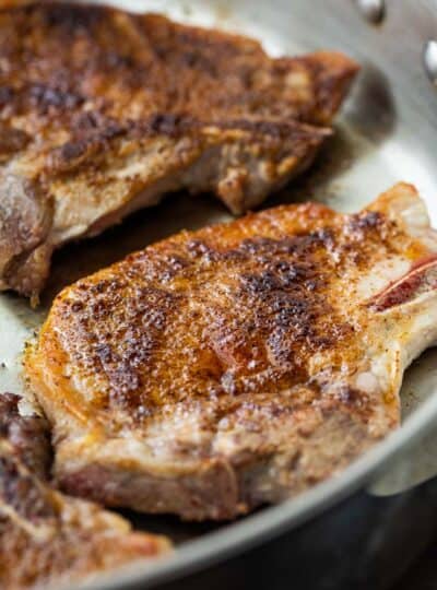 Close up of thin pork chops in a skillet.