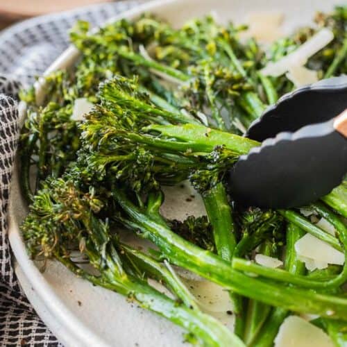 tongs picking up broccolini stem