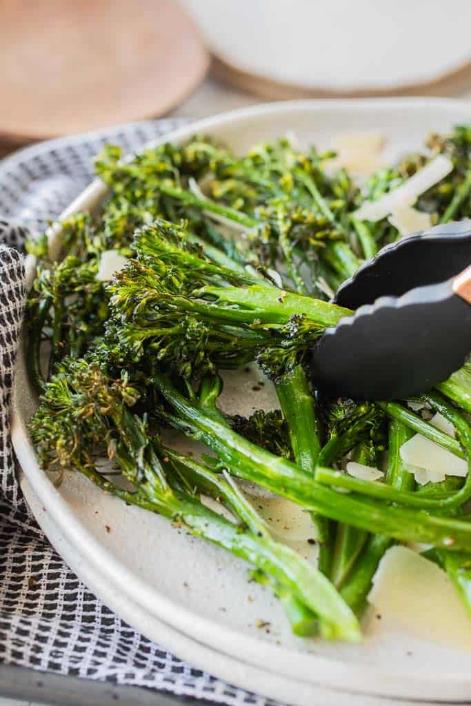 tongs picking up broccolini stem